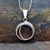 Silver circular pendant necklace on a stone background